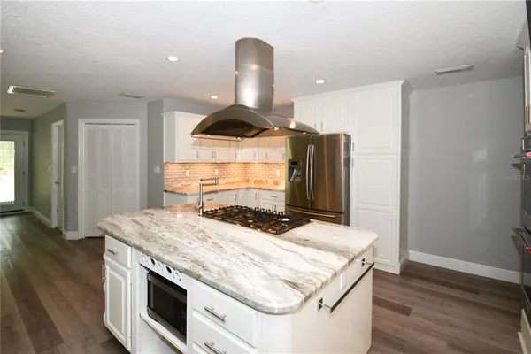 a kitchen with a stove and wooden floor