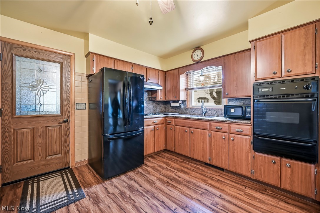 267 Butler Road Northeast Warren, OH 44483 - Photo 24 of 50 Kitchen with black appliances, a warming drawer, dark wood finished floors, wood finish cabinets, and tasteful backsplash