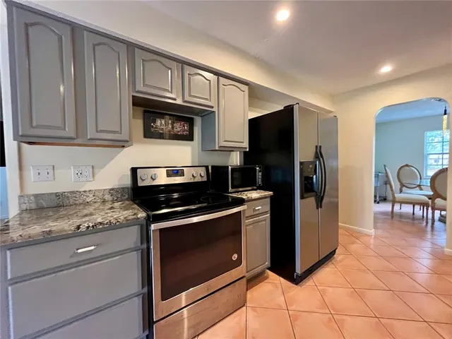 a kitchen with granite countertop a refrigerator and a stove top oven