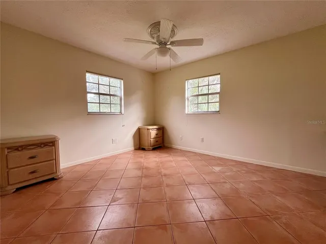 a view of an empty room with a window and a ceiling fan