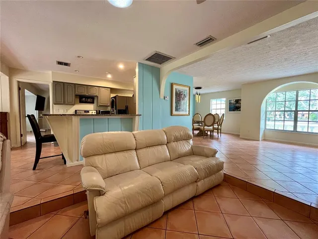 a living room with furniture kitchen view and a wooden floor