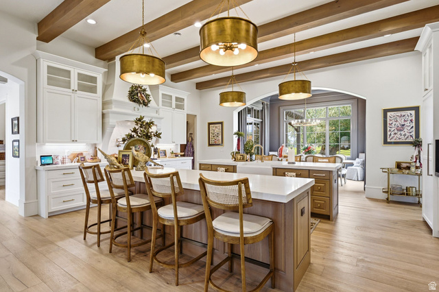 71 Farm Road Midway, UT 84049 - Photo 13 of 92 Gourmet kitchen featuring a dual island design, light wood-finish flooring, exposed wood ceiling beams, white cabinetry with glass-front accents, and a built-in range hood