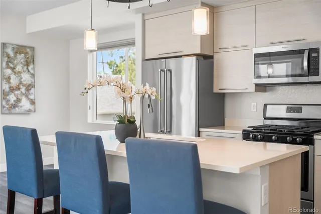 a kitchen with stainless steel appliances granite countertop a stove a refrigerator a microwave a sink and white cabinets