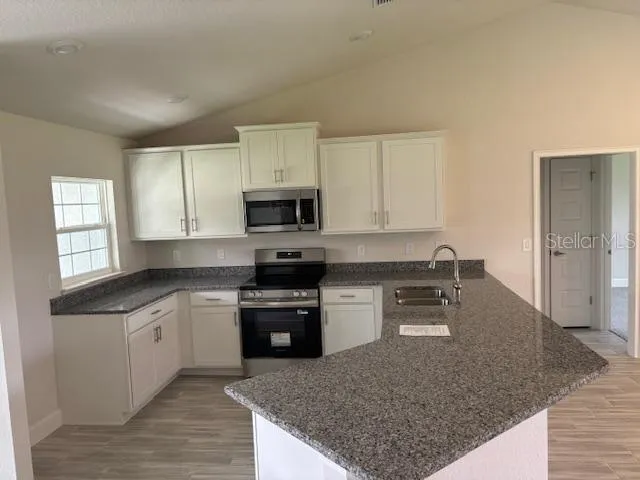 a kitchen with stainless steel appliances granite countertop a sink a stove and a wooden floors