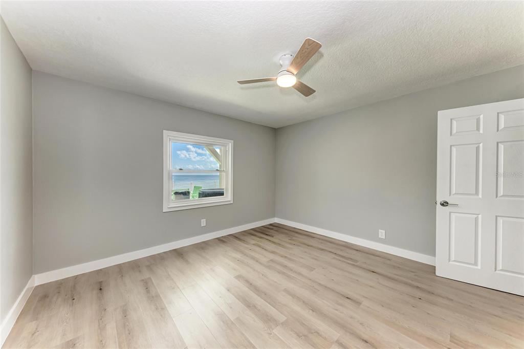 893 North Shore Drive Anna Maria, FL 34216 - Photo 28 of 62 an empty room with wooden floor chandelier fan and windows