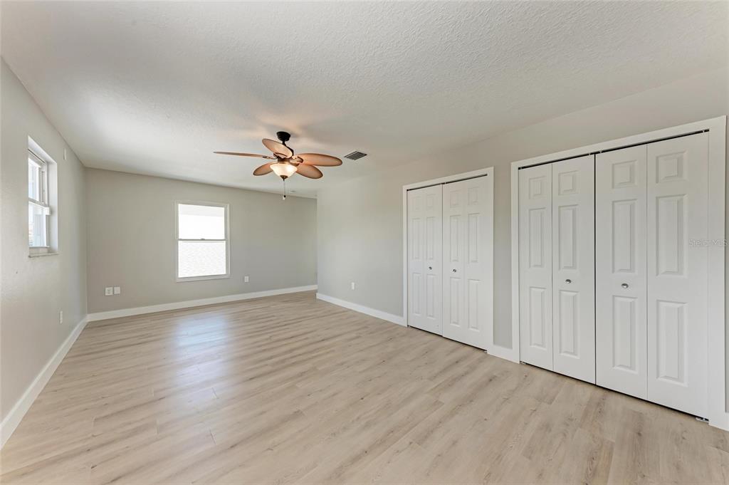 893 North Shore Drive Anna Maria, FL 34216 - Photo 34 of 62 an empty room with wooden floor chandelier fan and windows