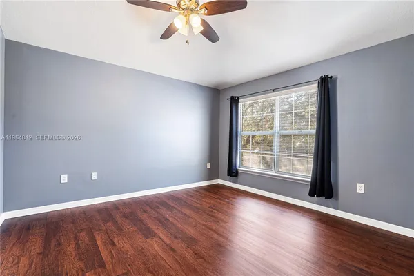 a view of an empty room with a window and wooden floor
