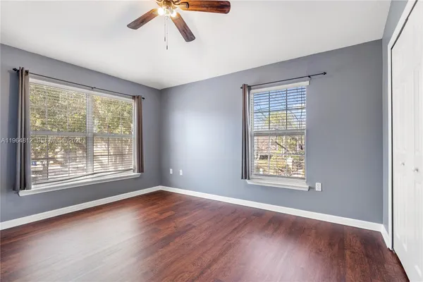 a view of an empty room with a window and wooden floor