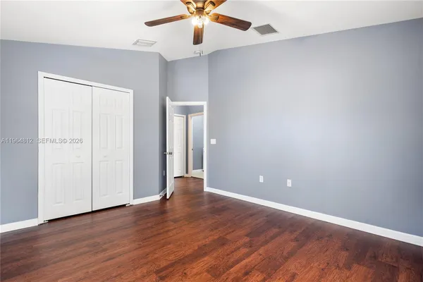 an empty room with wooden floor chandelier fan and closet area
