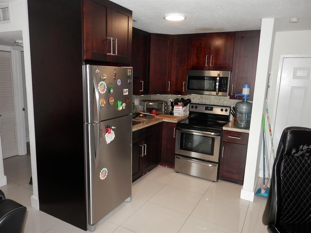 9459 Southwest 76th Street, Unit R1 Miami, FL 33173 - Photo 4 of 7 a kitchen with stainless steel appliances granite countertop a refrigerator and a stove top oven