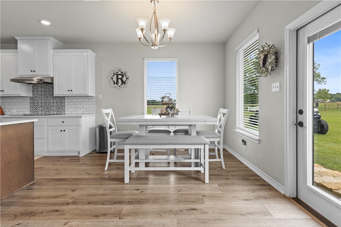 596 J W Martine Road Hearne, TX 77859 - Photo 11 of 36 a dining room with wooden floor a chandelier a wooden table and chairs