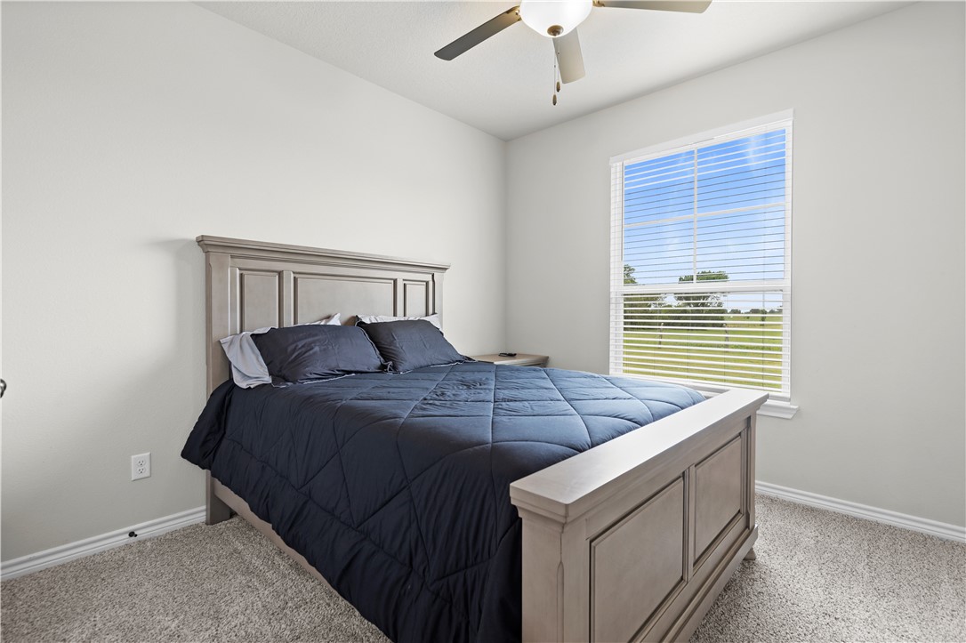 596 J W Martine Road Hearne, TX 77859 - Photo 19 of 36 a bed sitting in a bedroom next to a window and a chandelier