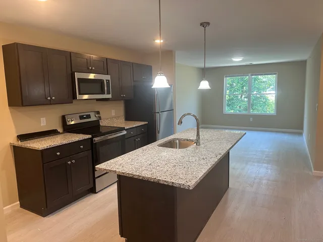a kitchen with kitchen island granite countertop a sink a counter top space appliances and cabinets