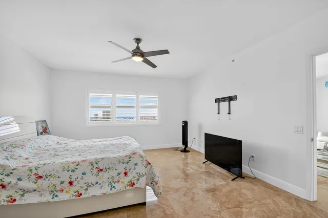 a bedroom with a large bed and a chandelier fan