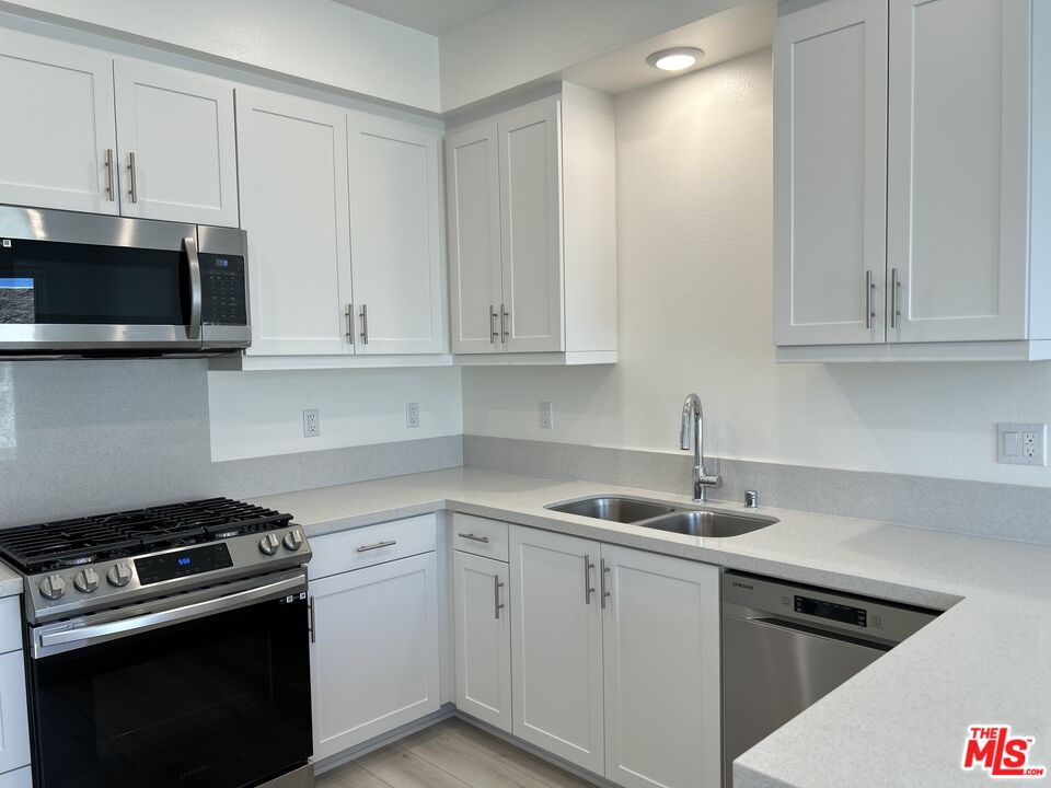 a kitchen with granite countertop white cabinets and stainless steel appliances