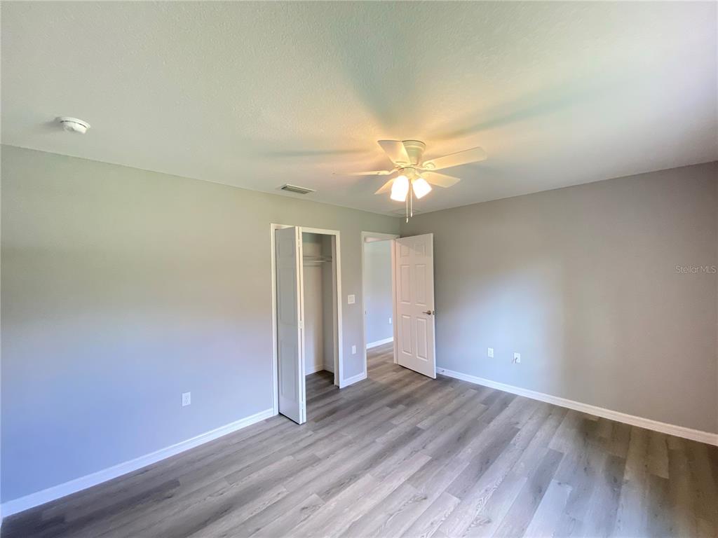 2458 Southwest 170th Loop Ocala, FL 34473 - Photo 13 of 25 an empty room with wooden floor and chandelier fan