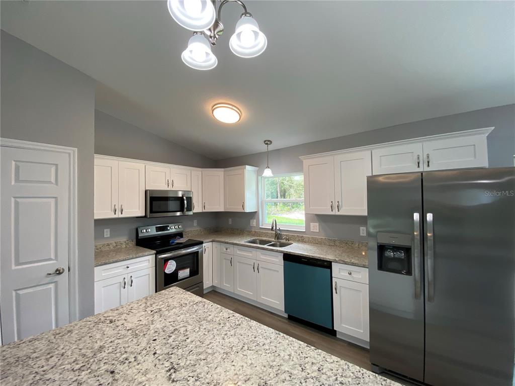 2458 Southwest 170th Loop Ocala, FL 34473 - Photo 7 of 25 a kitchen with kitchen island granite countertop stainless steel appliances a sink stove and refrigerator