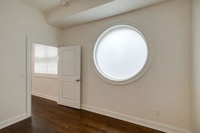 an empty room with wooden floor and a window