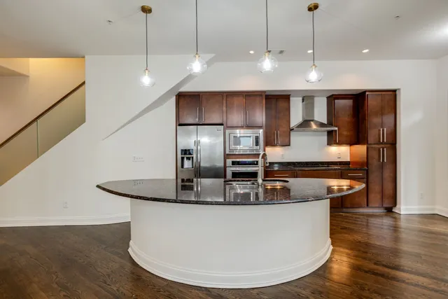 a kitchen with stainless steel appliances granite countertop a sink a microwave and a refrigerator