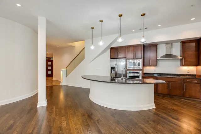 a kitchen with stainless steel appliances granite countertop a sink a stove and a wooden floors