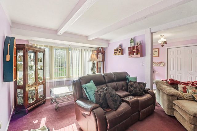 a living room with furniture kitchen view and a large window