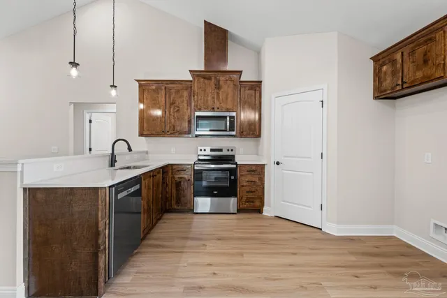 a kitchen with stainless steel appliances granite countertop a stove top oven a sink and a refrigerator