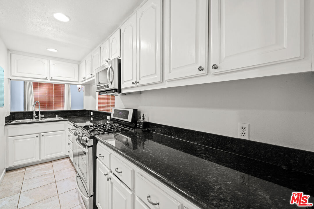 1401 South Bentley Avenue, Unit 202 Los Angeles, CA 90025 - Photo 2 of 32 a kitchen with stainless steel appliances granite countertop a sink a stove and white cabinets