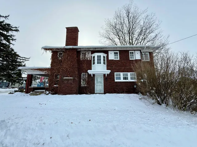 a front view of a house with a yard covered in snow