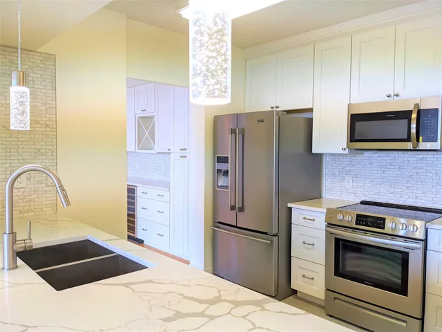 a kitchen with stainless steel appliances kitchen island granite countertop a refrigerator stove and sink