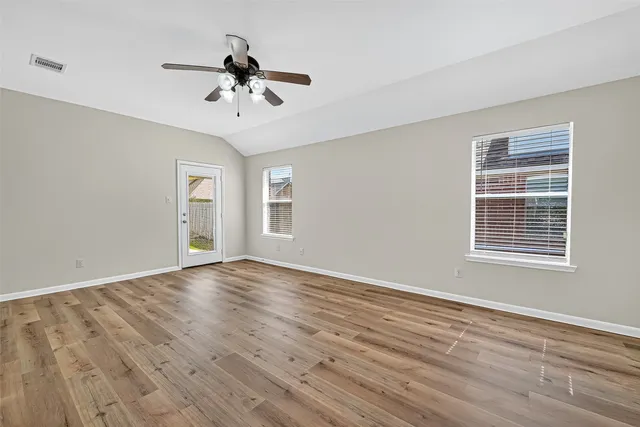 a view of an empty room with wooden floor and a window
