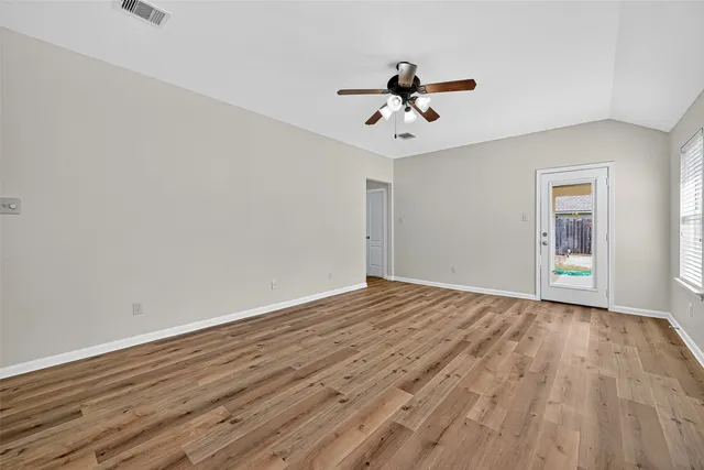 a view of empty room with wooden floor and fan