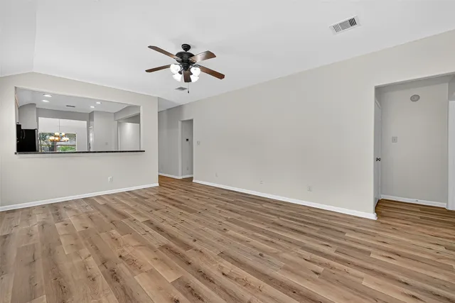 a view of empty room with wooden floor and fan