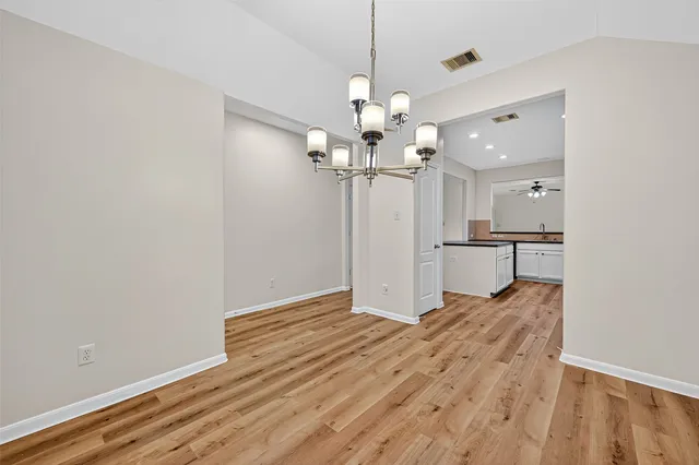 a view of a room with a chandelier and wooden floor