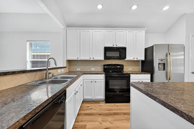 a large kitchen with granite countertop a sink dishwasher stove and refrigerator