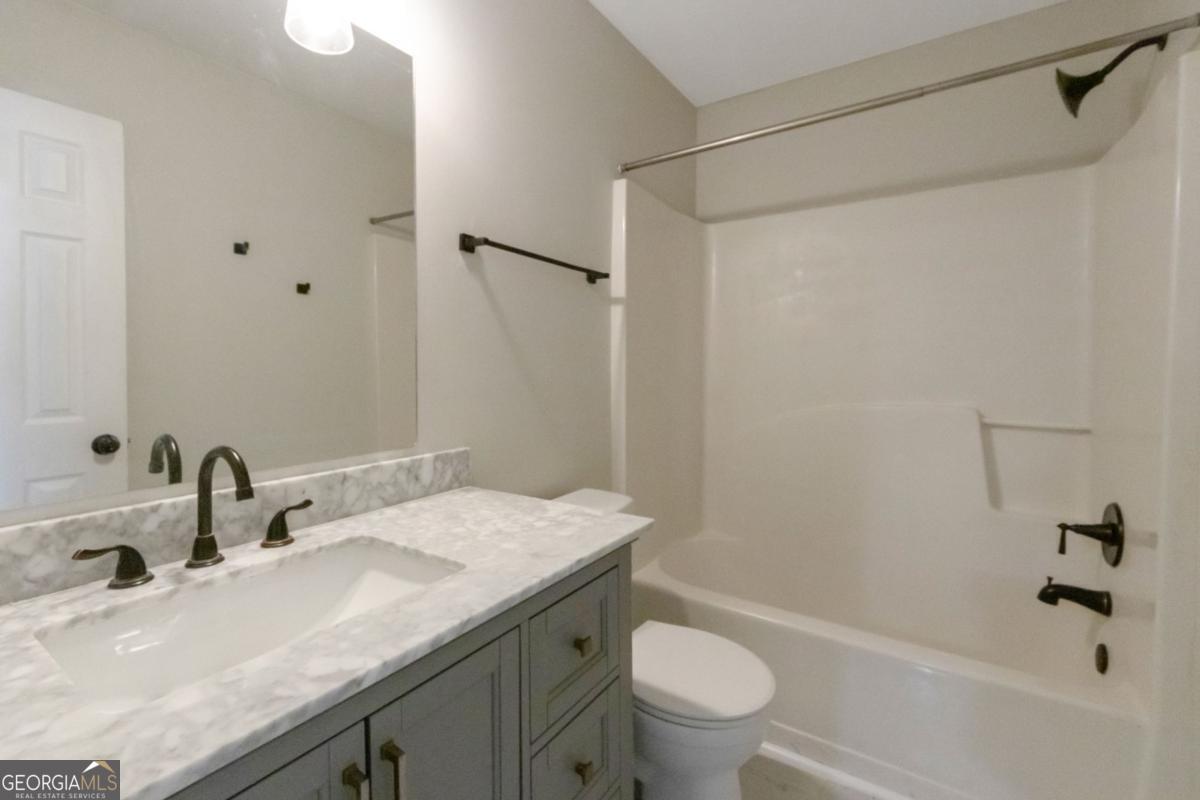 5920 Seabright Lane Atlanta, GA 30349 - Photo 13 of 18 a bathroom with a granite countertop sink toilet and shower
