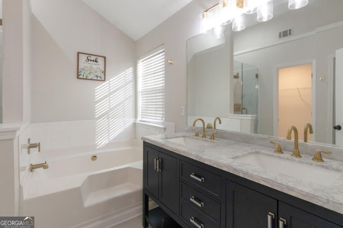 5920 Seabright Lane Atlanta, GA 30349 - Photo 10 of 18 a bathroom with a granite countertop sink mirror and a bath tub