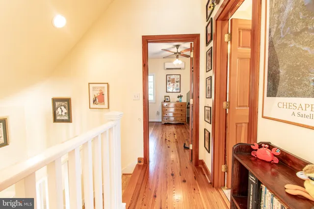 a view of a hallway to a livingroom with wooden floor and furniture