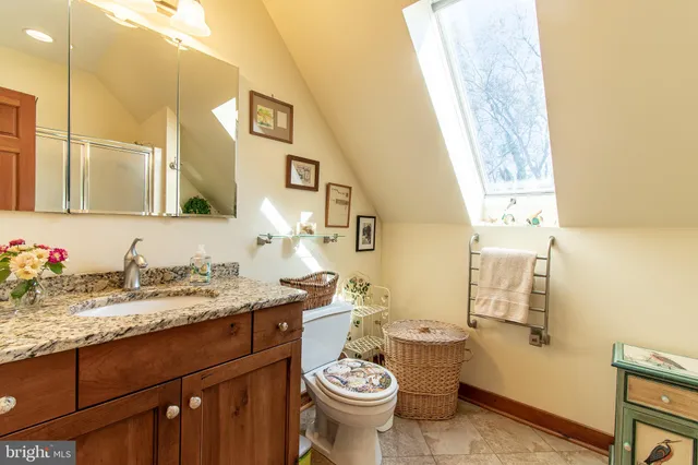 a bathroom with a granite countertop sink mirror and toilet