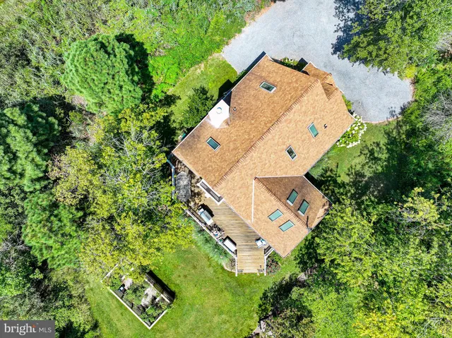 an aerial view of a house with swimming pool and large trees