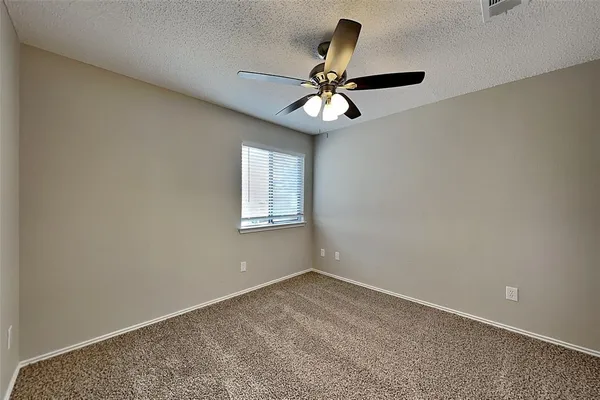 an empty room with a window and a fan