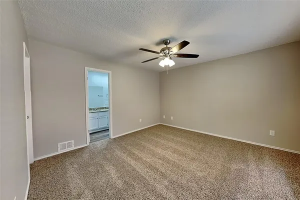 an empty room with a chandelier fan and a table