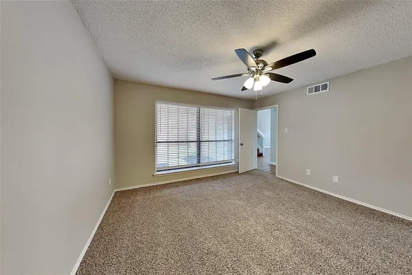 an empty room with chandelier fan and windows