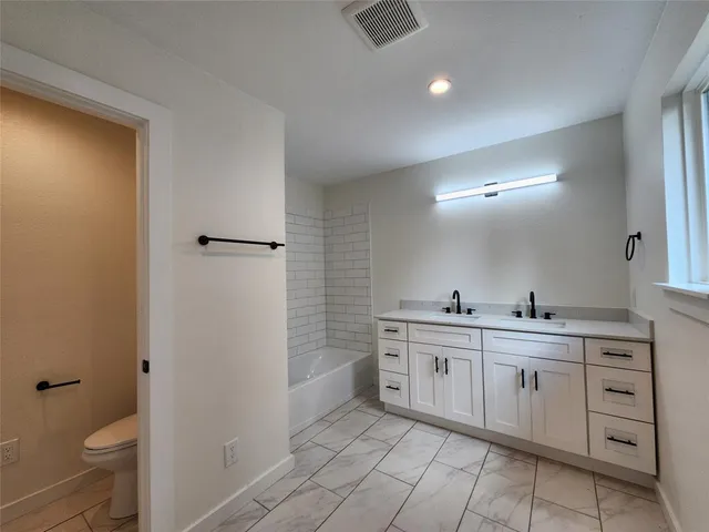 a spacious bathroom with a granite countertop sink a toilet and a shower