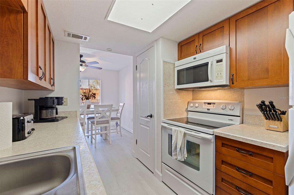 8911 Blind Pass Road, Unit 319 St. Pete Beach, FL 33706 - Photo 15 of 29 a kitchen with stainless steel appliances a stove a sink a microwave and wooden cabinets