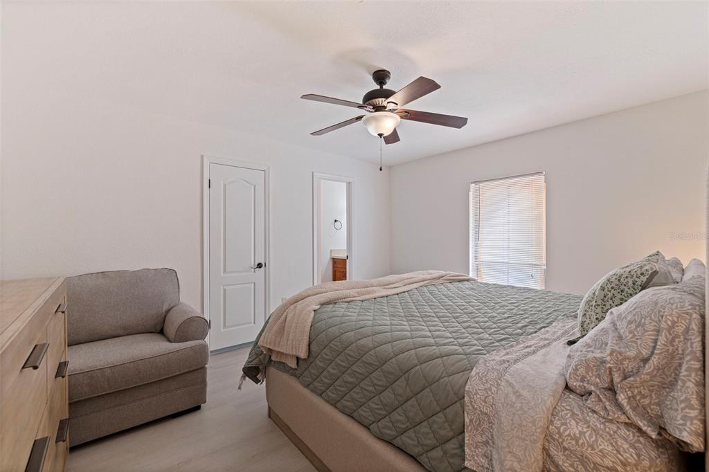 8911 Blind Pass Road, Unit 319 St. Pete Beach, FL 33706 - Photo 17 of 29 a spacious bedroom with a bed a couch and a chandelier