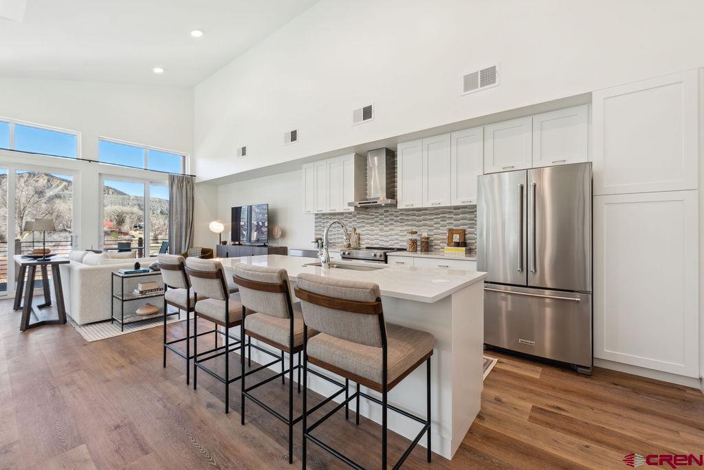 185 Riverfront Lane, Unit D1 B Ridgway, CO 81432 - Photo 17 of 35 a kitchen with stainless steel appliances a refrigerator a stove a sink dishwasher and a dining table with wooden floor