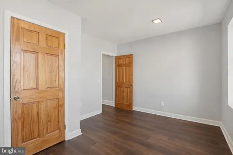 an empty room with wooden floor and closet area