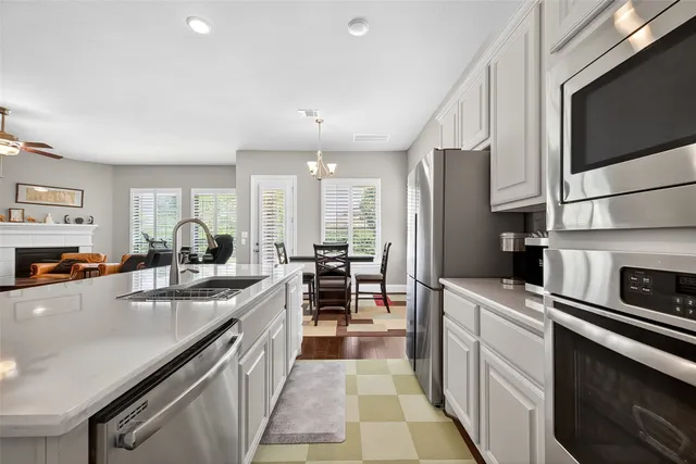 a kitchen with stainless steel appliances a refrigerator a stove a sink dishwasher and white cabinets with wooden floor