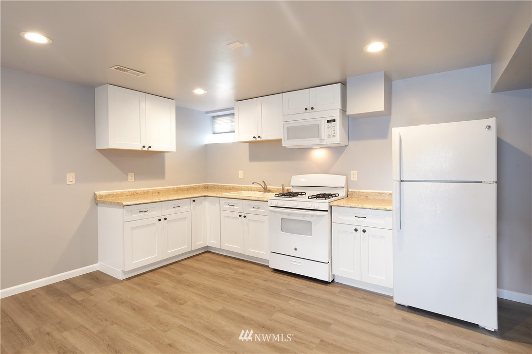 1606 Bayon Road Bellingham, WA 98225 - Photo 15 of 39 a kitchen with granite countertop a refrigerator stove a sink and white cabinets with wooden floor