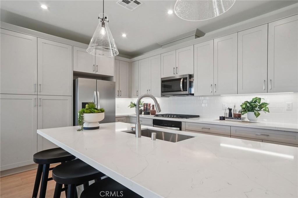 73634 Raphael Drive Palm Desert, CA 92211 - Photo 11 of 42 a kitchen with stainless steel appliances a table chairs and a refrigerator
